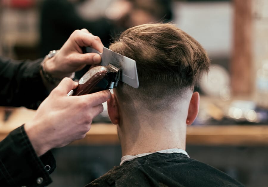 Hairdresser cutting a high skin fade haircut on a male client