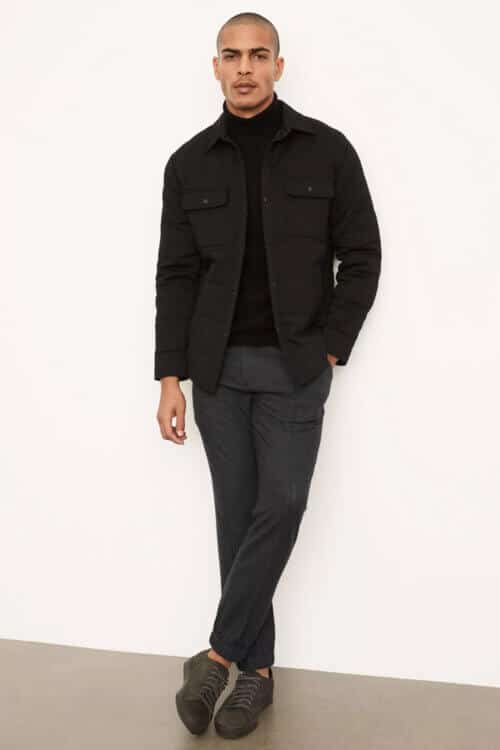 Men's all black outfit with black roll neck, overshirt, chinos and sneakers
