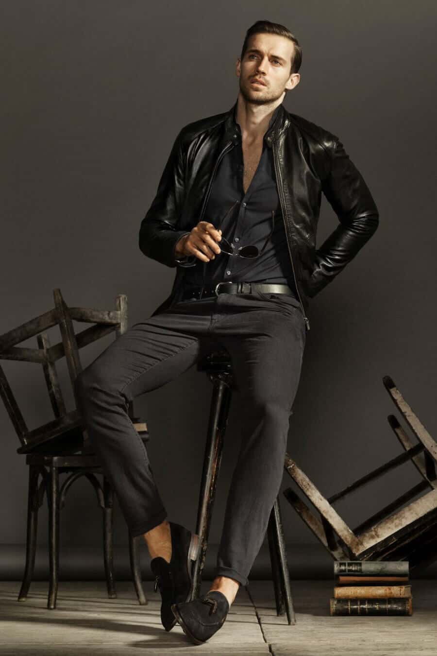 Men's slick all black outfit with black shirt, leather jacket, jeans and suede loafers
