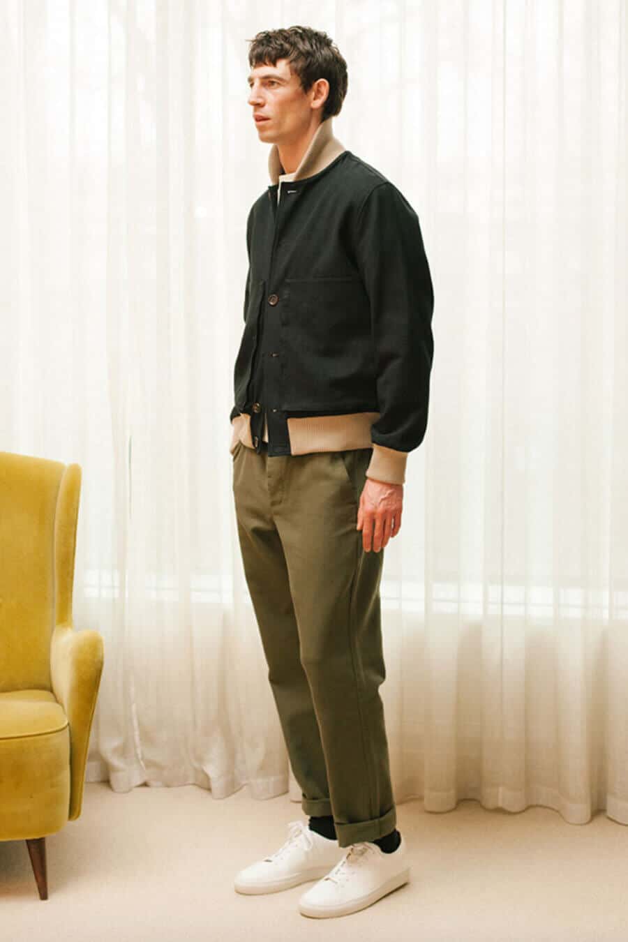 Men's olive green pants, navy bomber jacket and white sneakers outfit