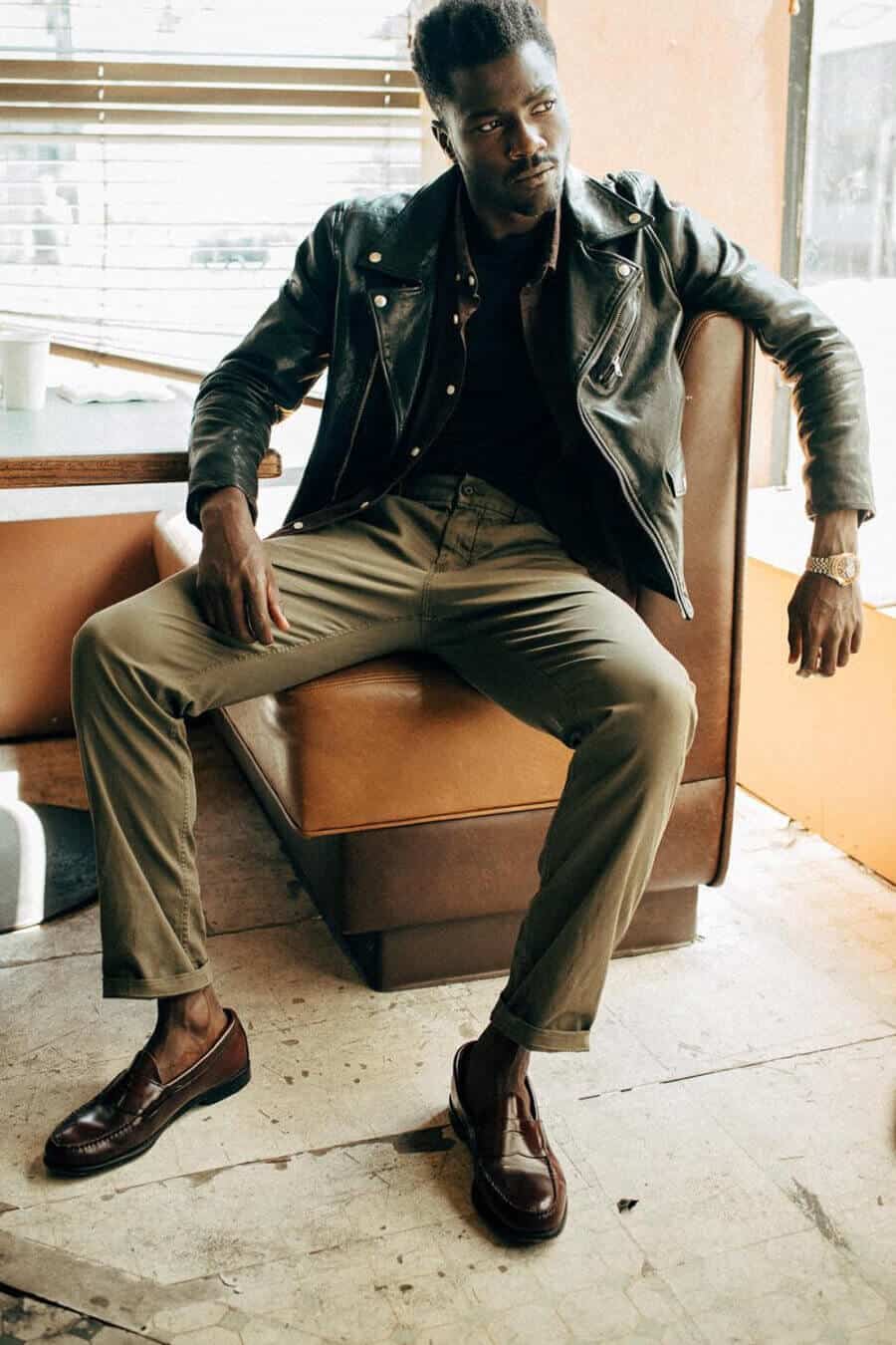Men's olive green pants, black leather jacket and penny loafers outfit