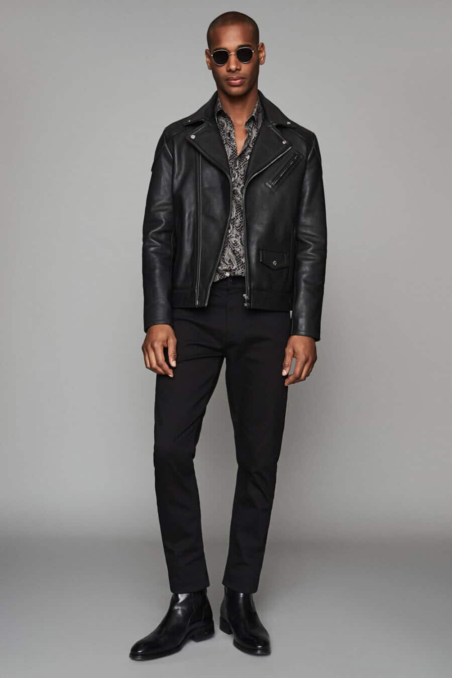 Men's black leather biker jacket, patterned shirt, jeans and boots outfit