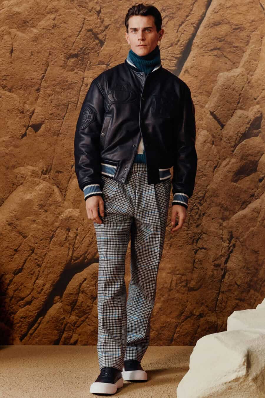Men's leather varsity jacket, roll neck, pleated trousers and sneakers outfit