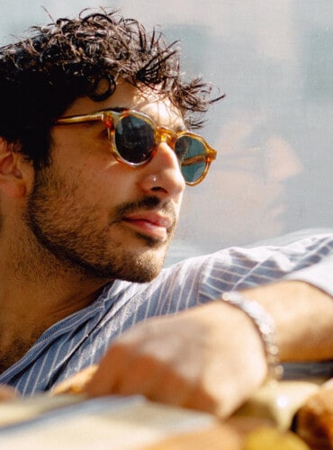 Man wearing a pair of cool brown tortoiseshell acetate sunglasses and a blue/white stripe shirt