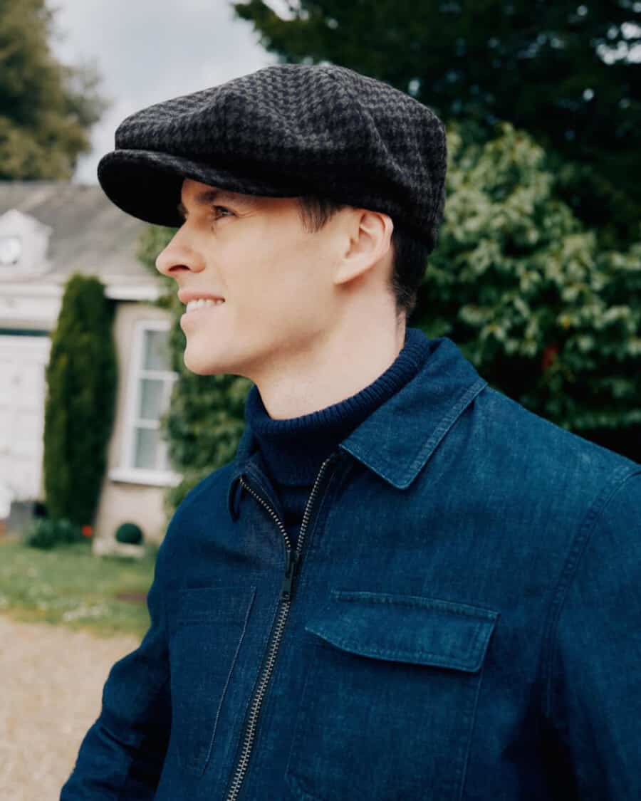 Man wearing a wool Lock & Co. baker boy hat with a blue denim zip-up jacket