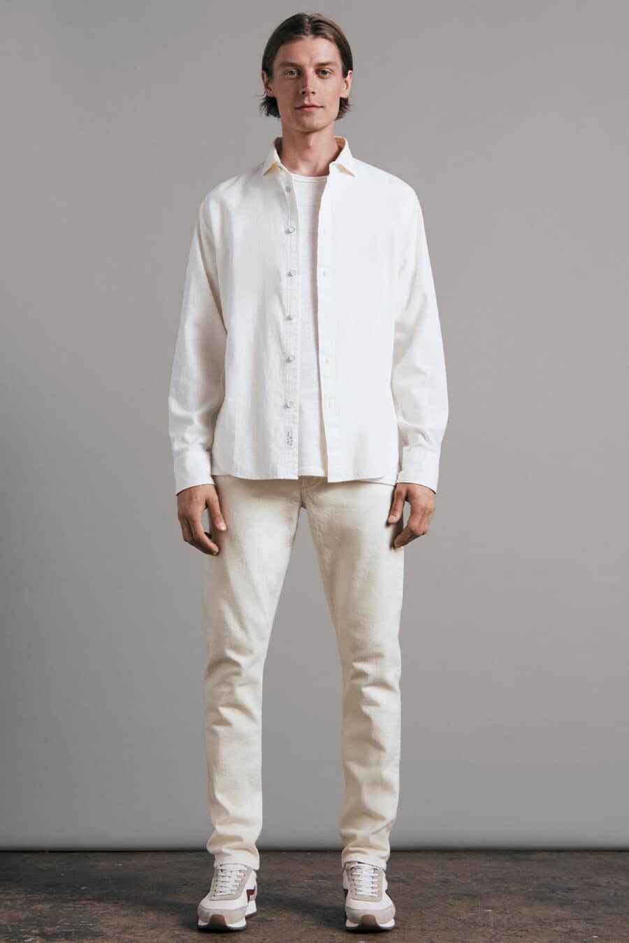 Men's off-white jeans, white T-shirt, white open overshirt and retro running sneakers outfit