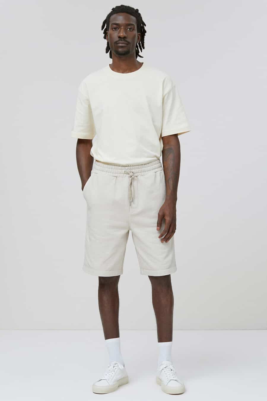 Men's off-white sweat shorts, off-white T-shirt, white tube socks and white sneakers outfit