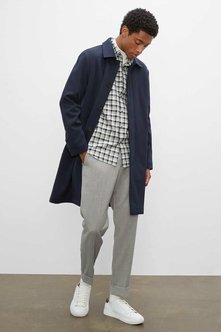 Men's spring flannel shirt outfit with grey chinos and lightweight rain coat