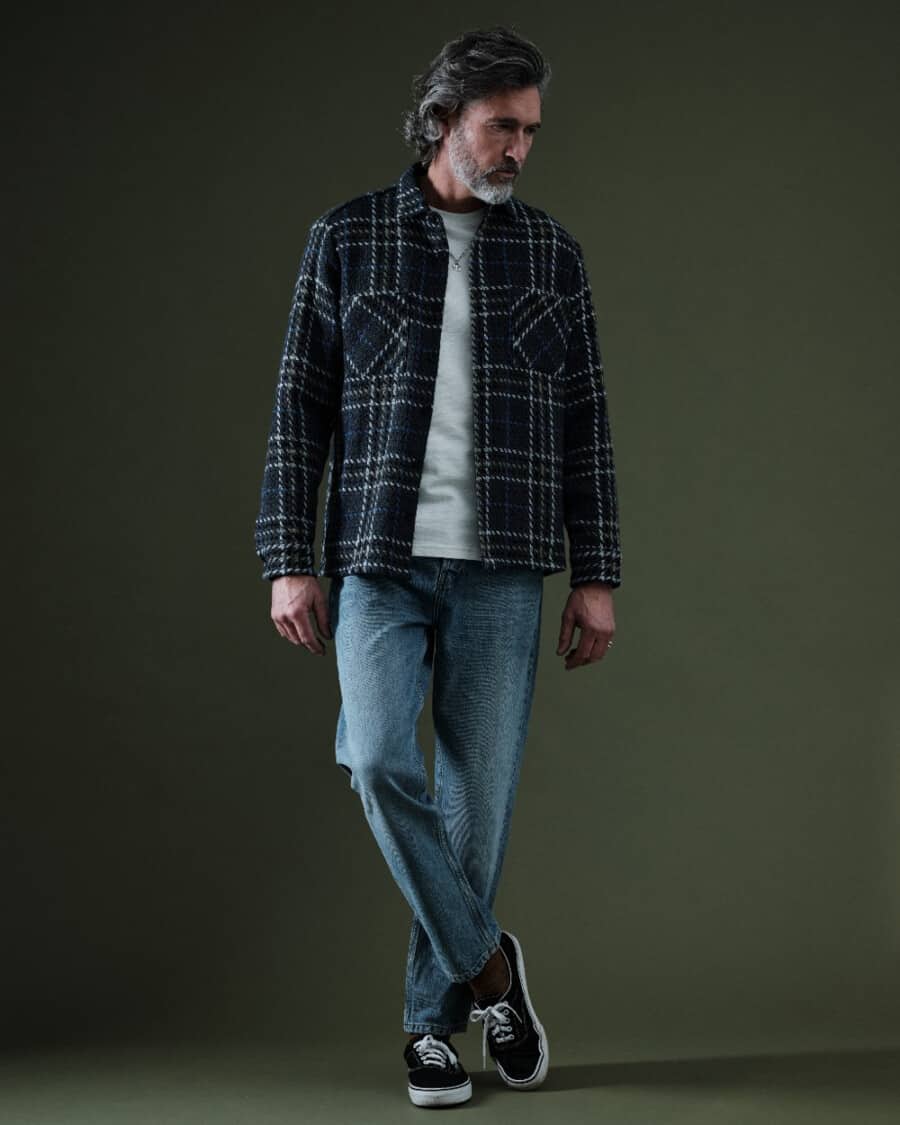 Men's stone washed denim jeans, white T-shirt, flannel check overshirt and black canvas sneakers outfit