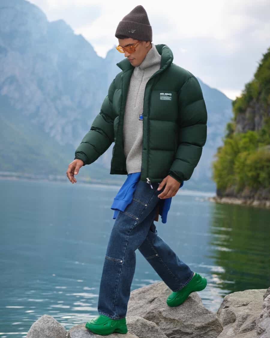 Men's denim work jeans, zip up fleece, green puffer jacket, green sneakers and grey beanie outfit