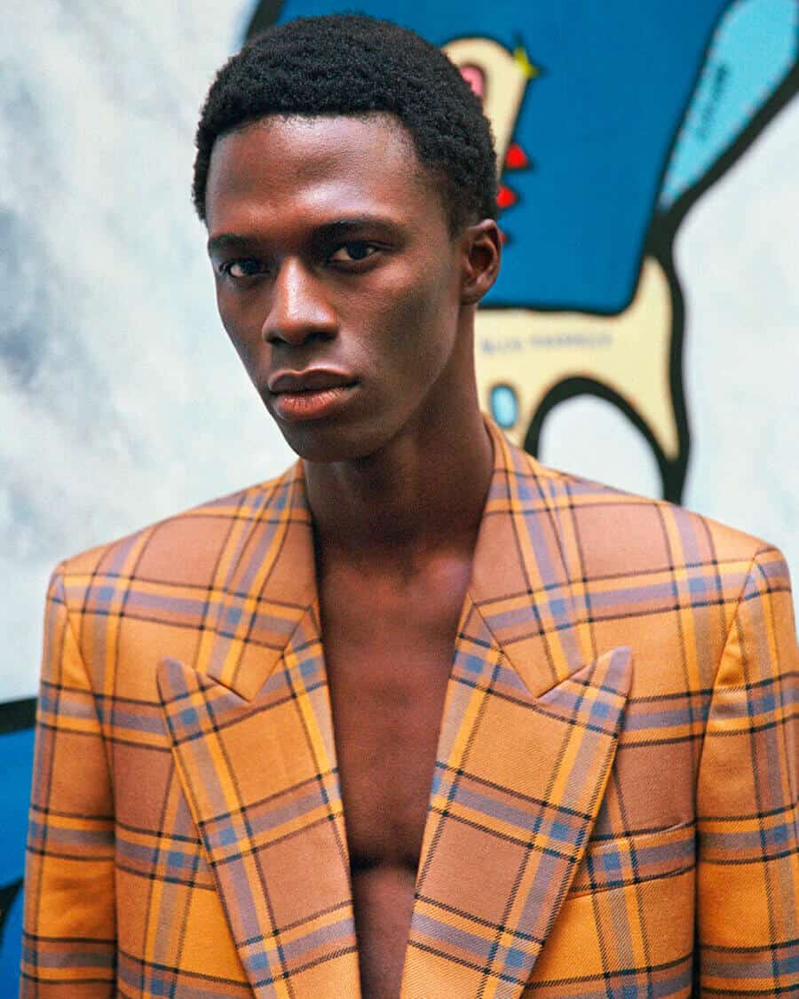Black male model Cherif Douamba wearing an orange and blue checked blazer