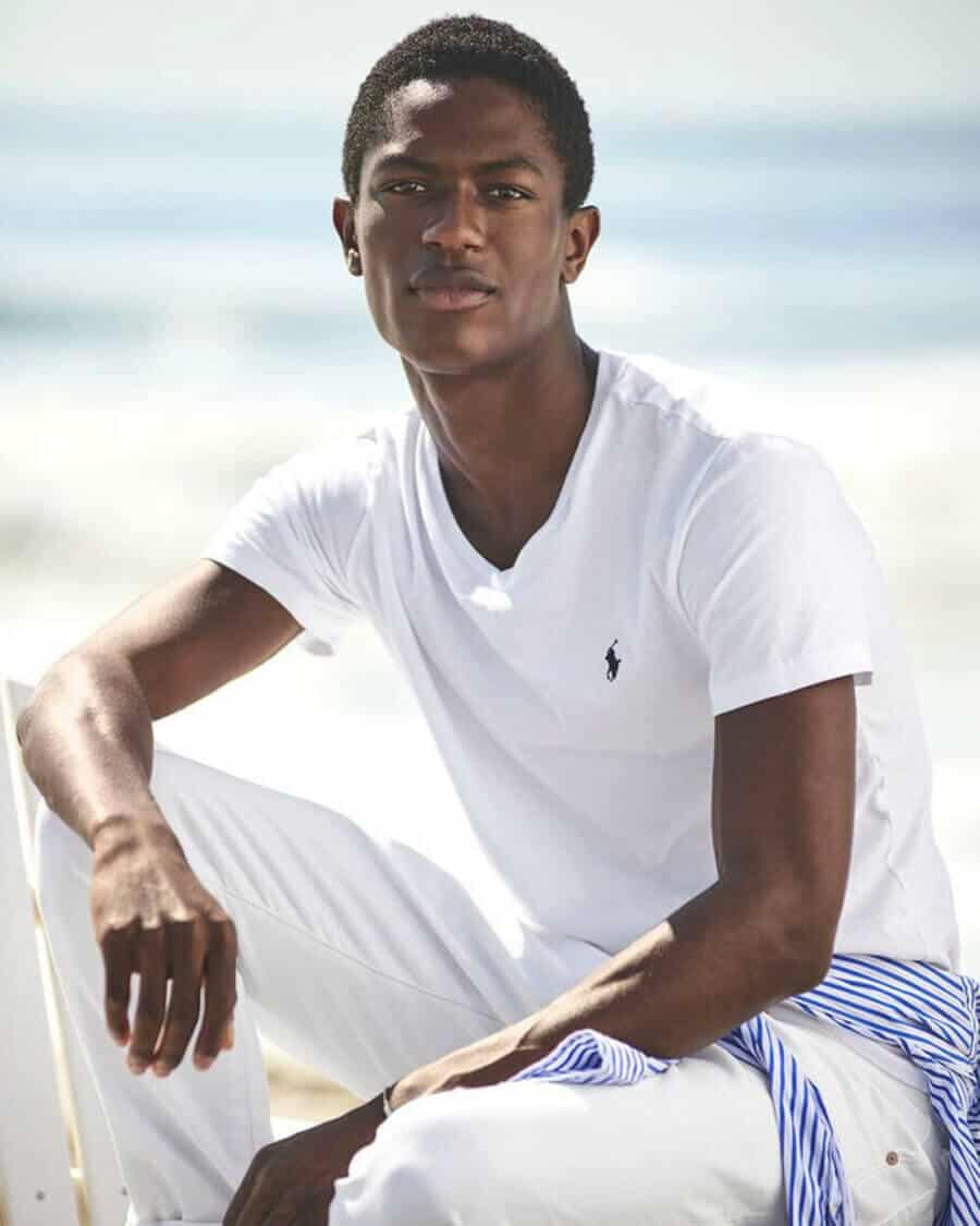 Black male model Hamid Onifadé wearing a white Ralph Lauren T-shirt with off-white chinos
