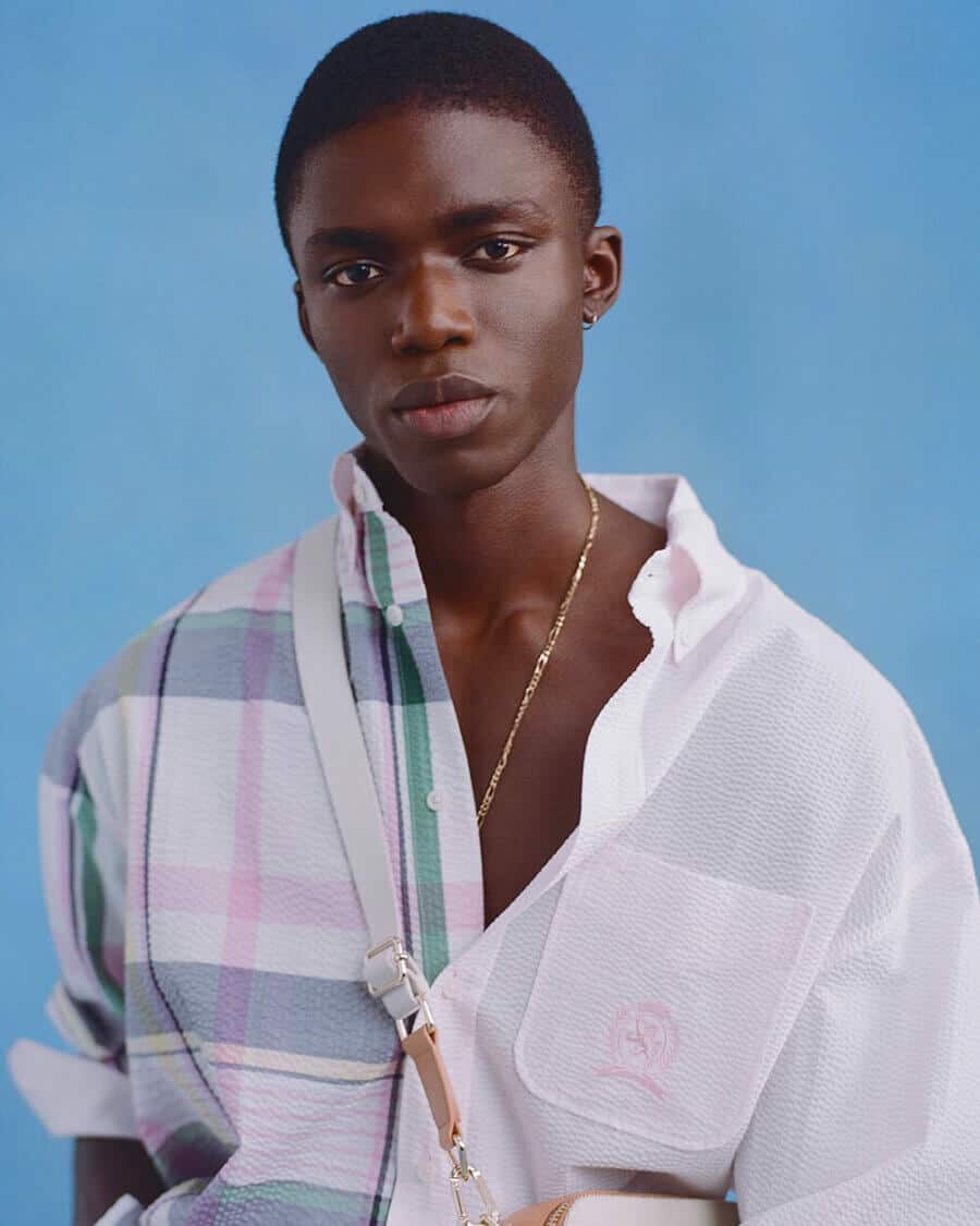 Black male model Jeremiah Berko Fourdjour wearing a white, pink and blue check shirt and gold chain necklace