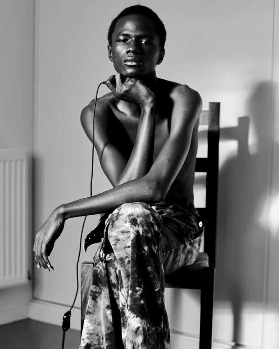Black male model Malick Bodian sitting on a chair