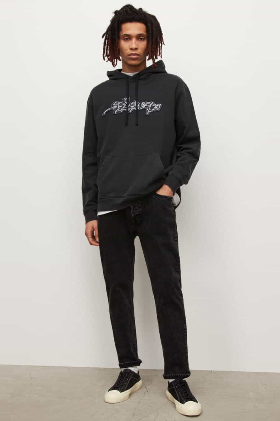 Men's black jeans, canvas sneakers and black hoodie outfit