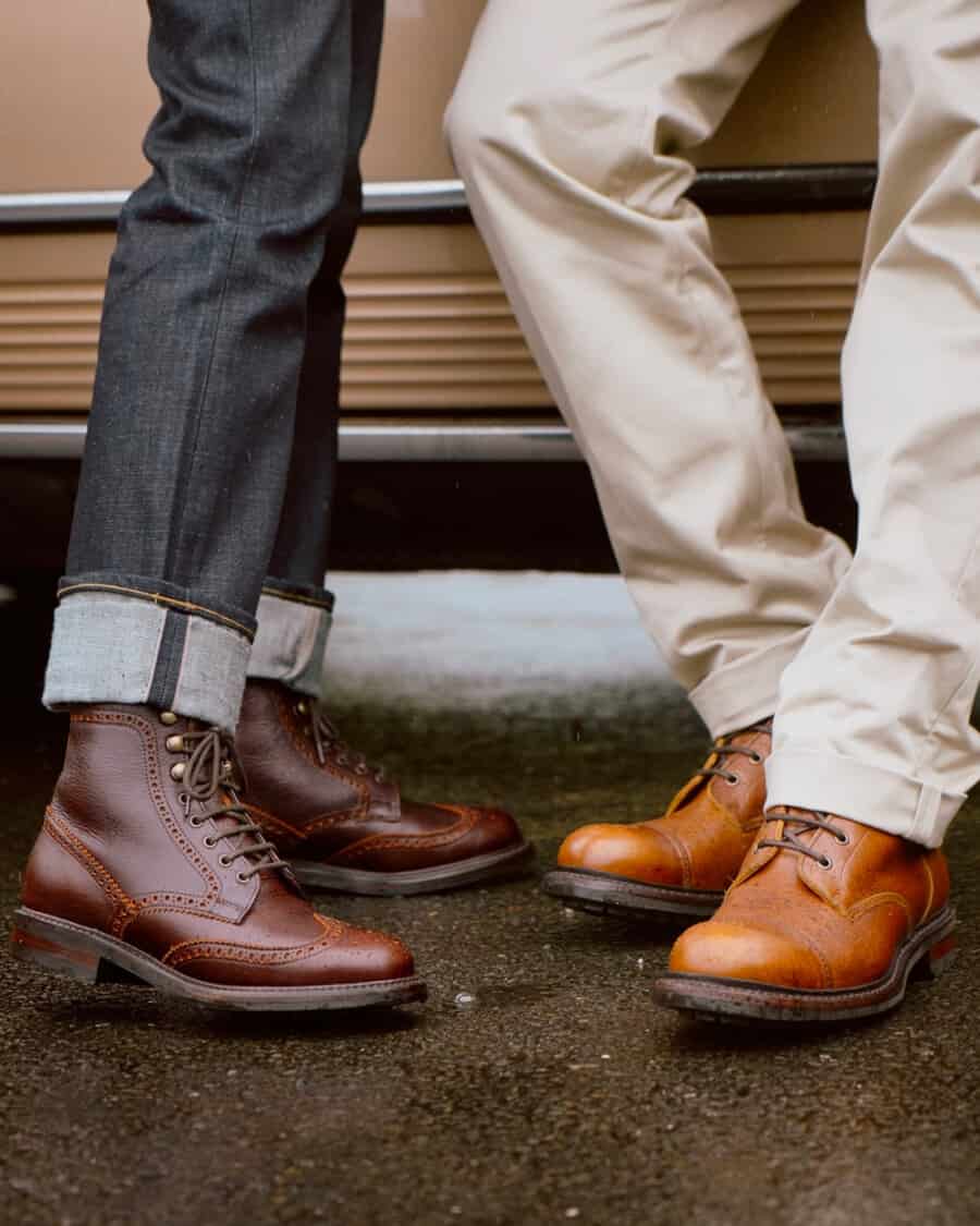 Men wearing Cheaney brown and tan leather boots on feet with raw denim jeans and off-white worker pants.