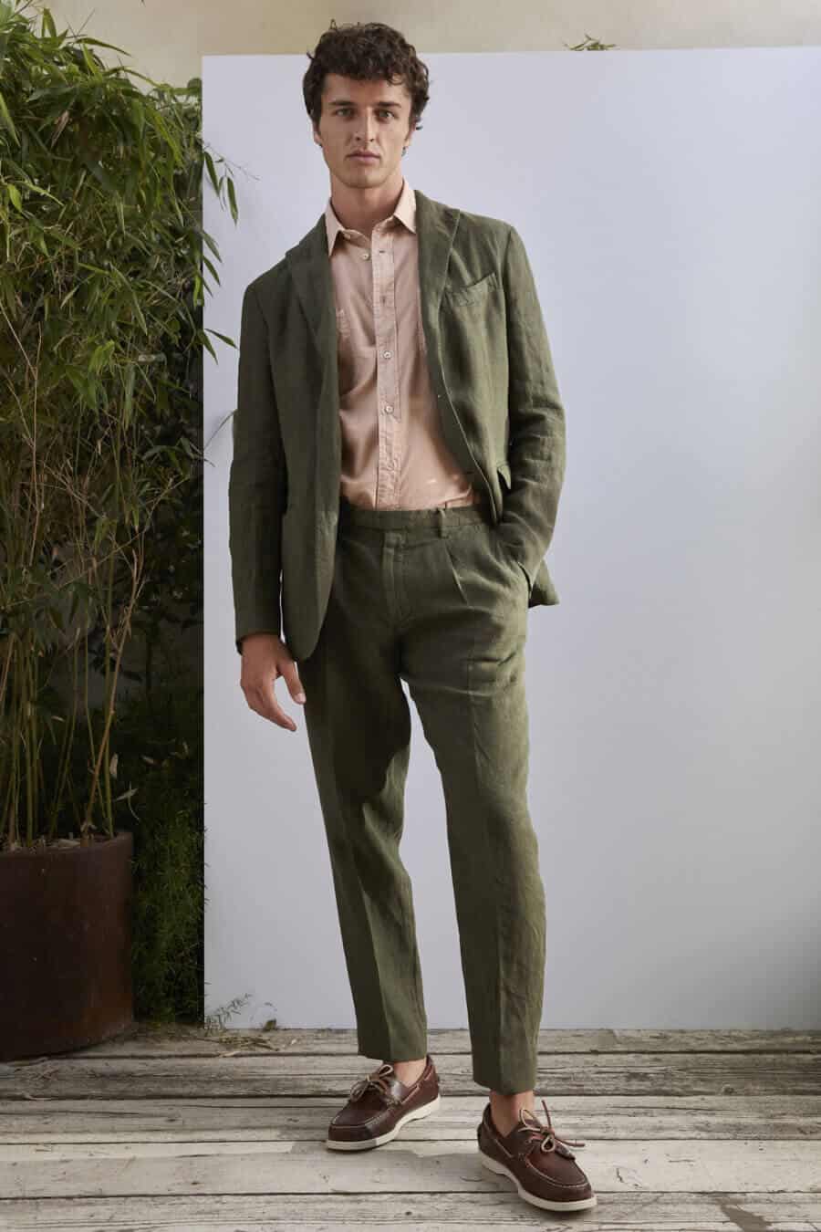 Men's olive green linen suit outfit worn with brown deck shoes
