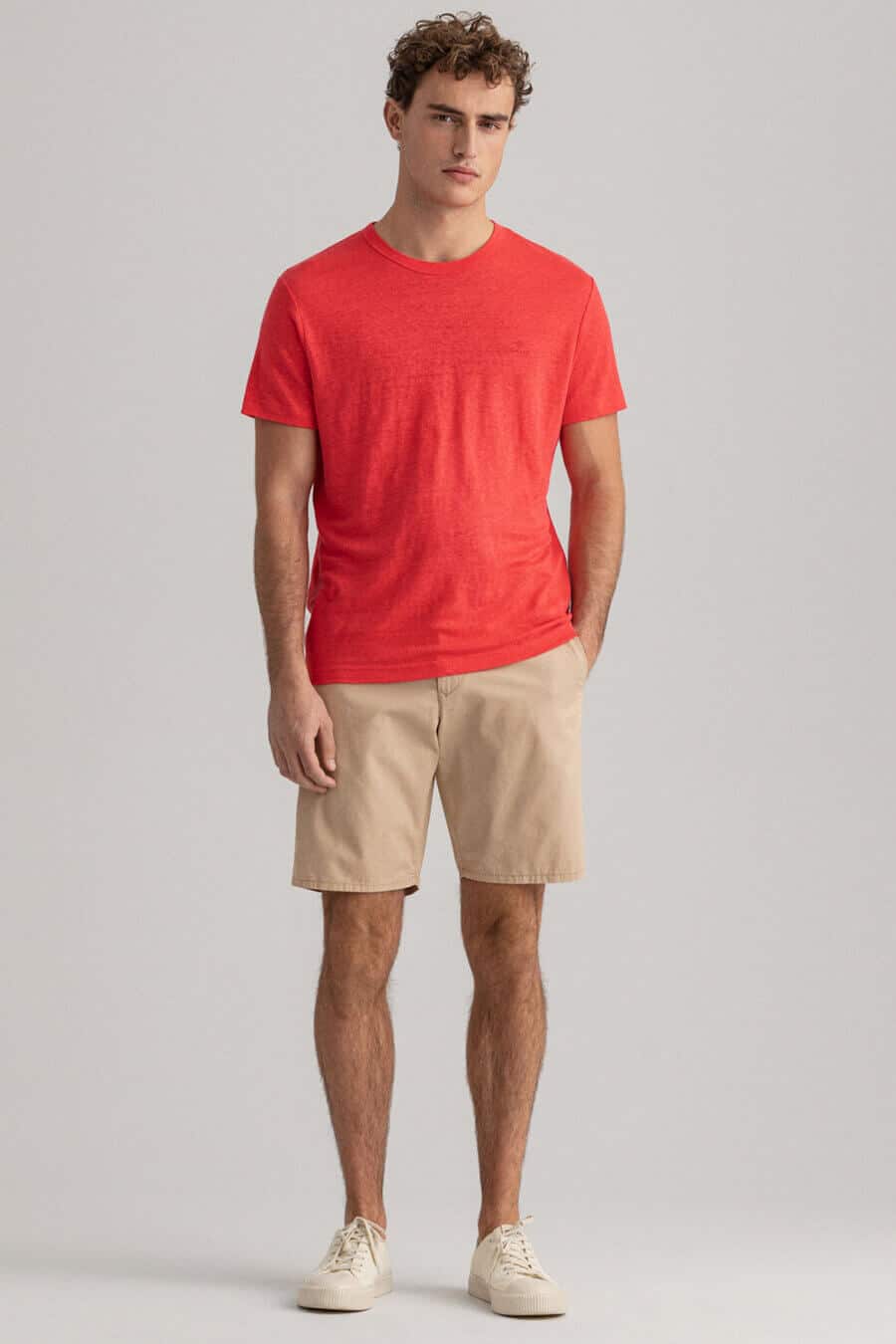 Men's red linen t-shirt with beige chino shorts and sneakers outfit