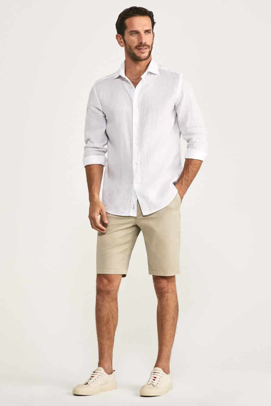 Men's white linen shirt with beige chino shorts and sneakers outfit