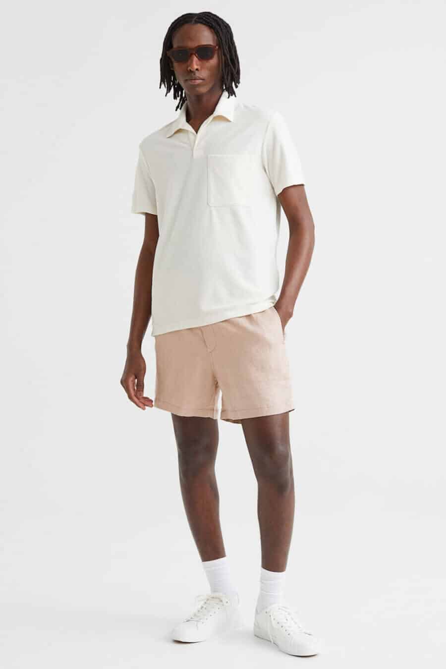 Men's pink linen shorts with white polo shirt and sneakers outfit