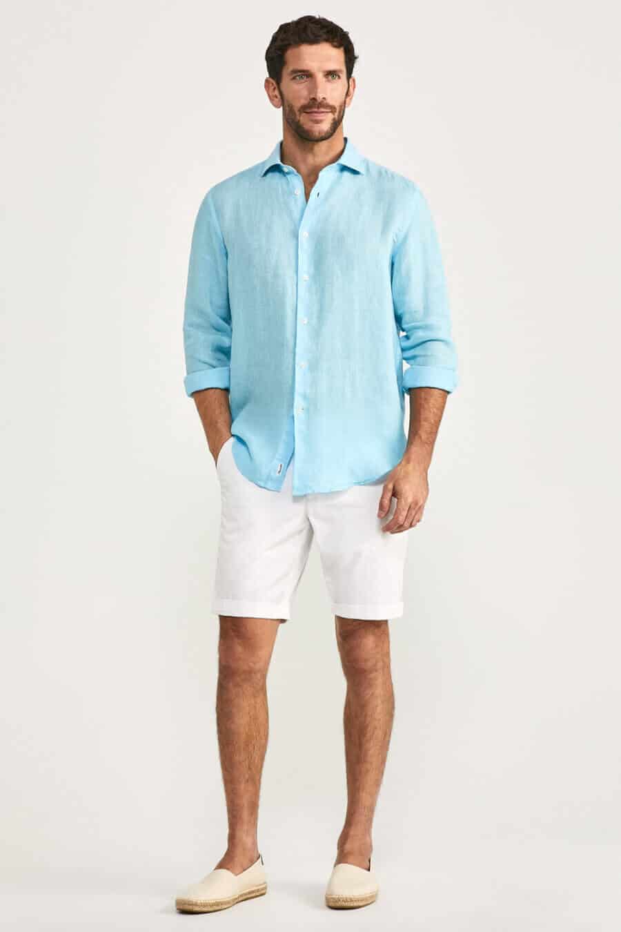 Men's white linen shorts with a bright blue shirt and espadrilles outfit