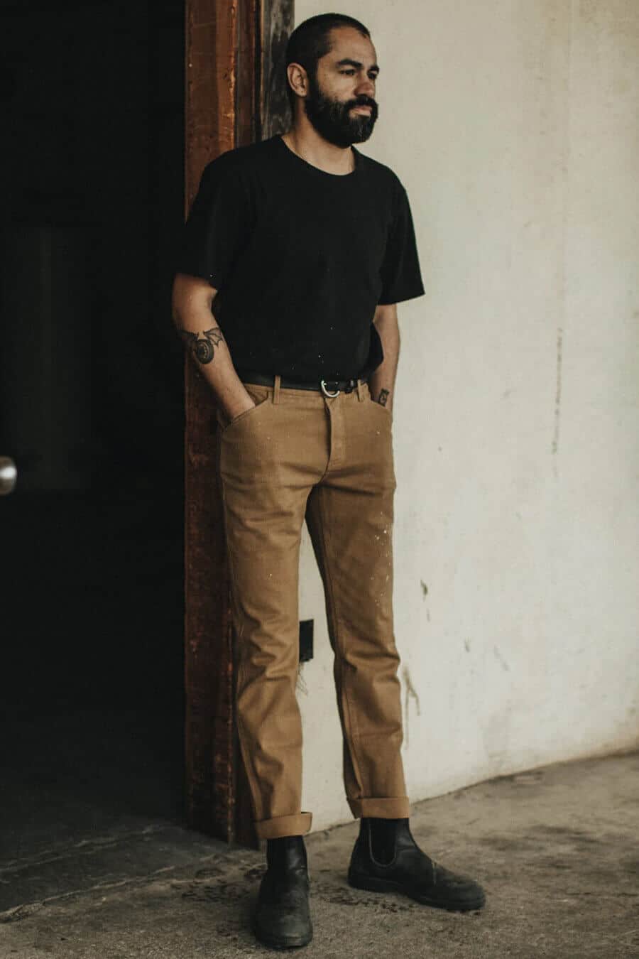 Men's simple khaki pants outfit with a black t-shirt and boots