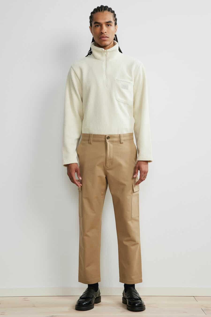 Men's khaki combat pants worn with a zip neck top and black loafers outfit