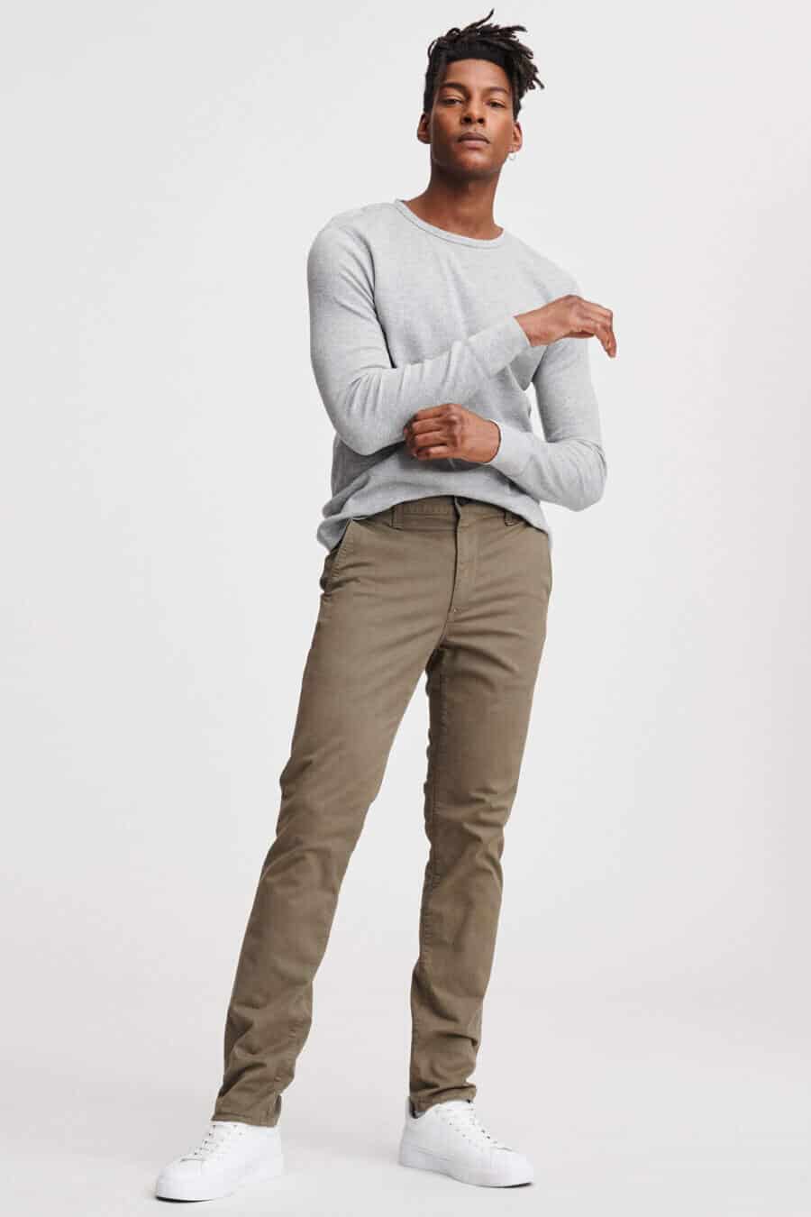 Men's khaki green pants worn with a grey sweatshirt and white sneakers