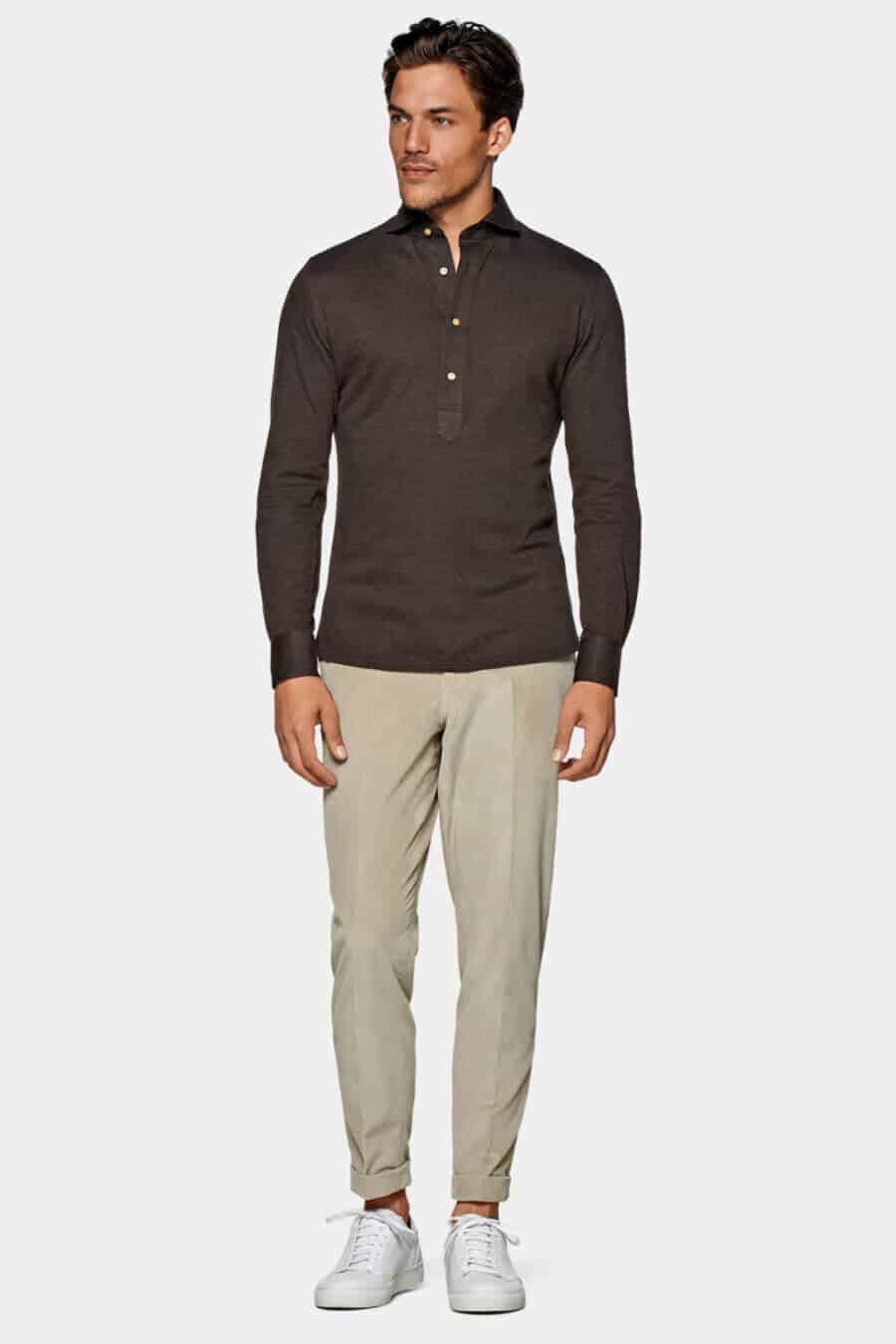 Men's khaki chinos worn with a brown knitted polo shirt and white sneakers look