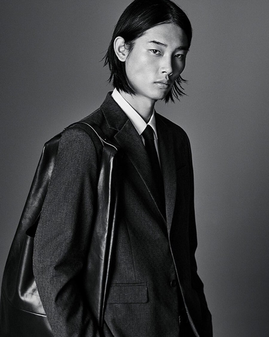 Korean male model Taemin Park wearing a charcoal suit with a white shirt and black tie