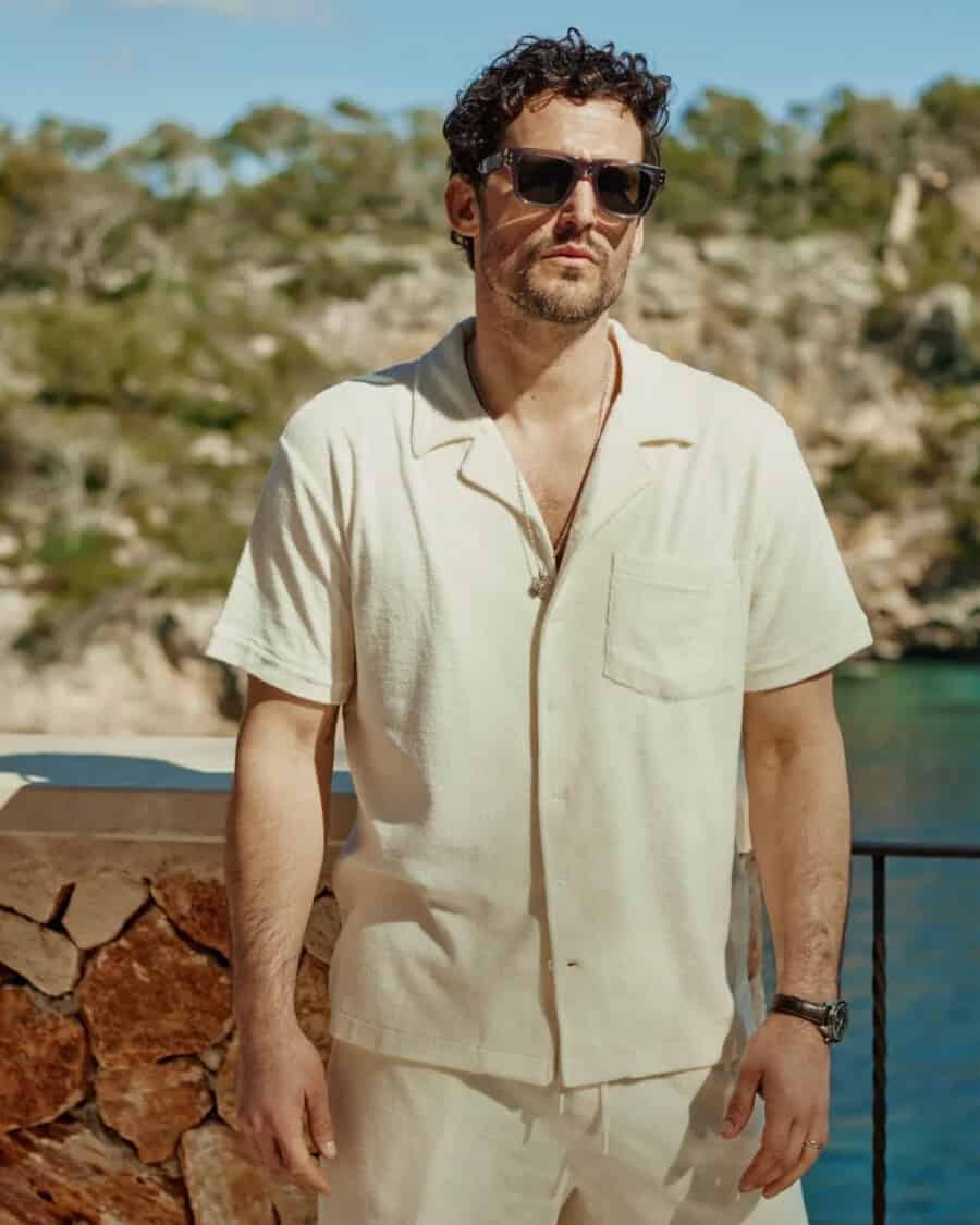 Man wearing an ivory Cuban collar shirt and matching shorts with dark sunglasses