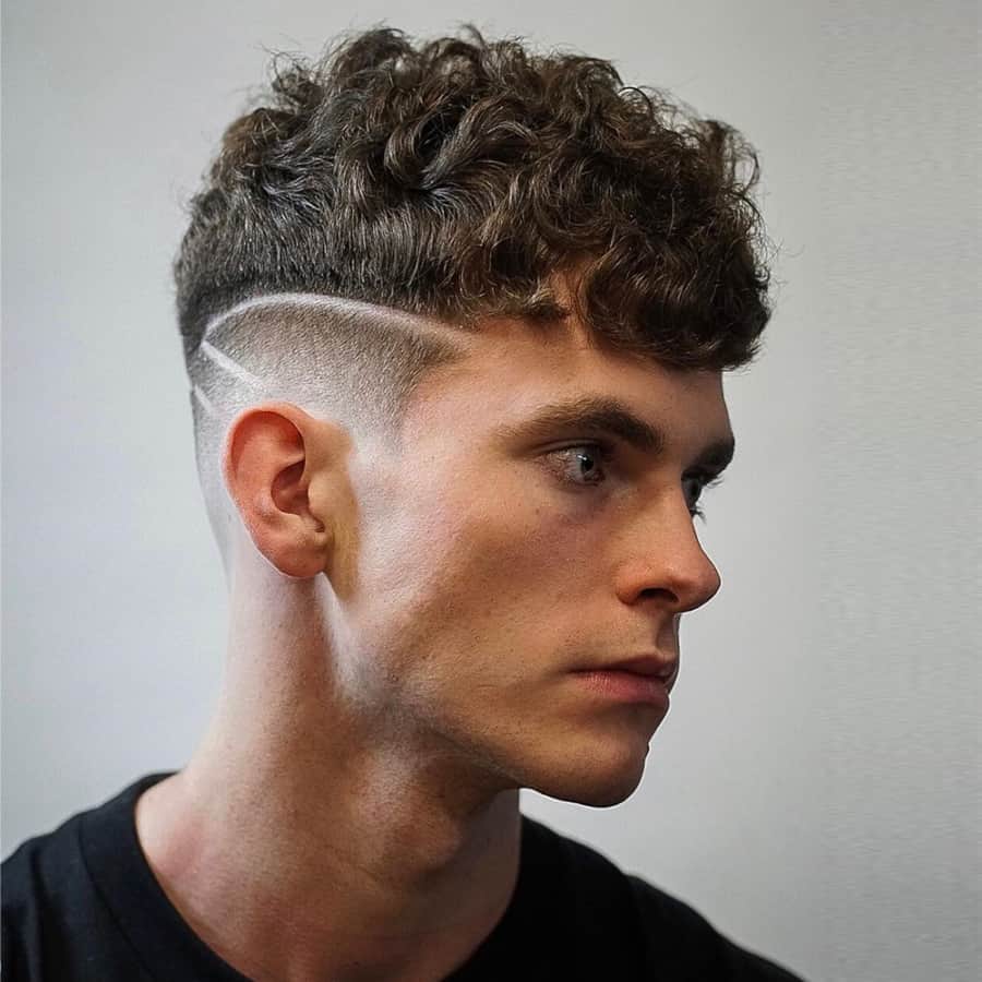 Men's curly fade haircut with clippered tram lines
