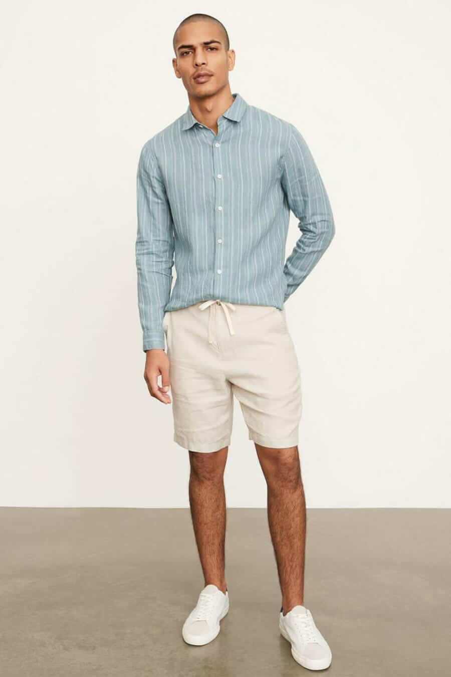 Men's smart casual summer outfit with linen shirt, tailored shorts and white sneakers