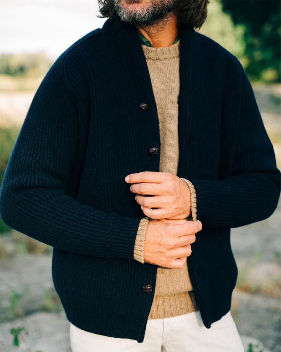 Man wearing white jeans, camel wool sweater and ribbed navy shawl cardigan