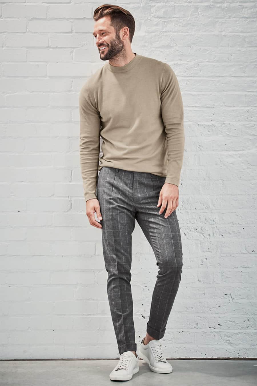 Men's grey checked pants, beige crew neck sweater and white sneakers outfit