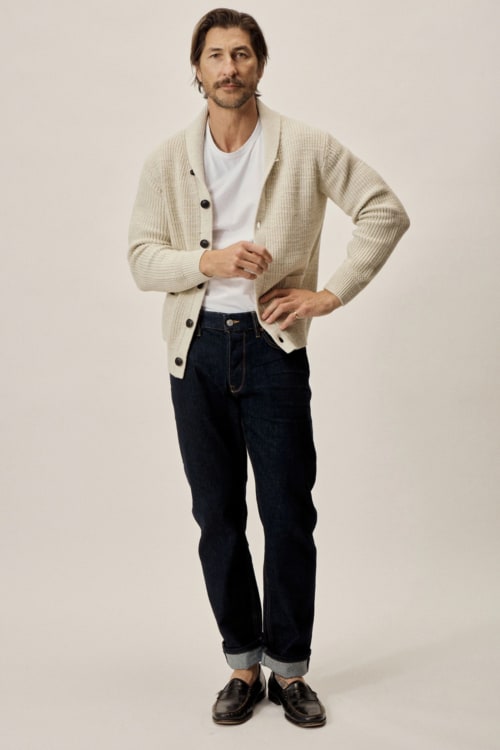 Men's preppy shawl neck cardigan worn with raw denim jeans, white T-shirt and leather penny loafers outfit