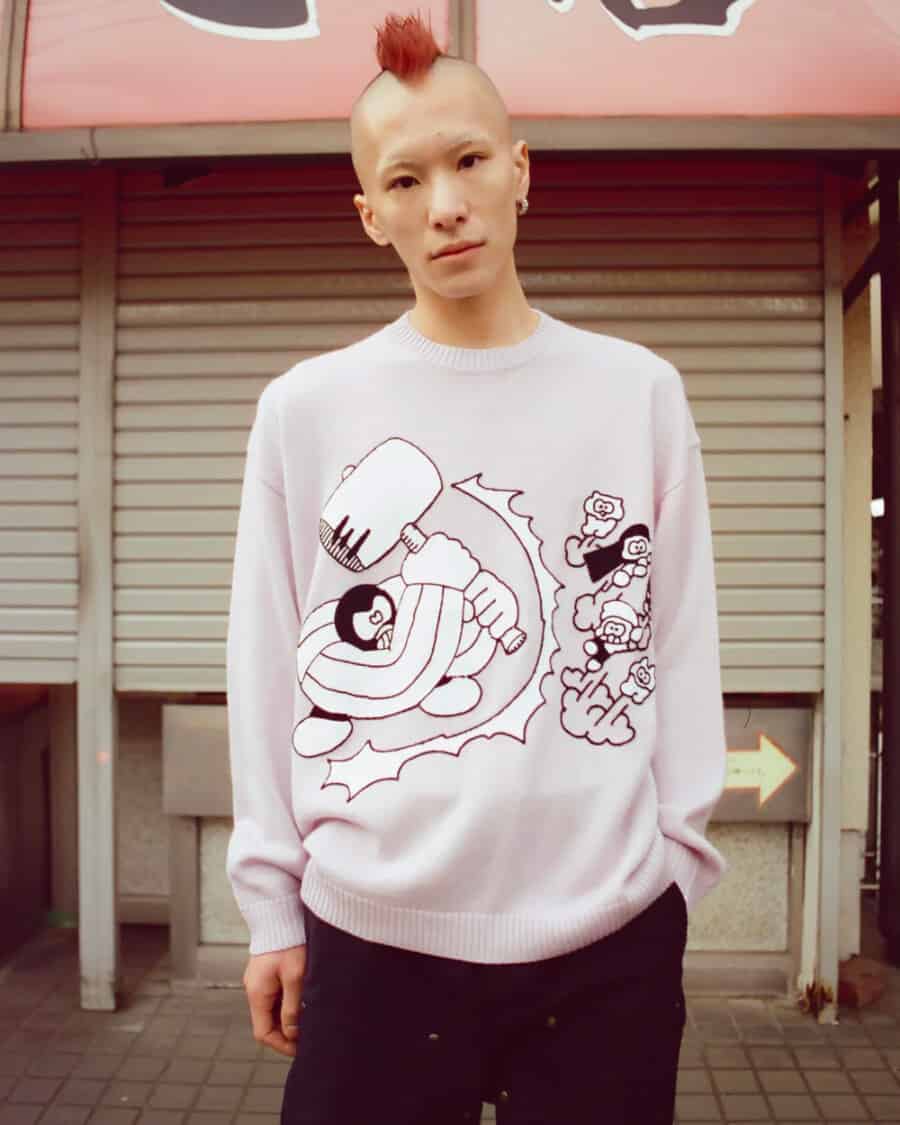 Man wearing Brain Dead streetwear graphic pink knit sweater and black pants