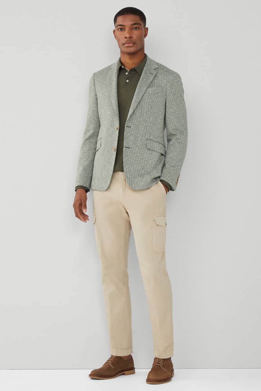 Men's khaki cargo pants, green polo shirt, green patterned blazer and brown suede Derby shoes outfit