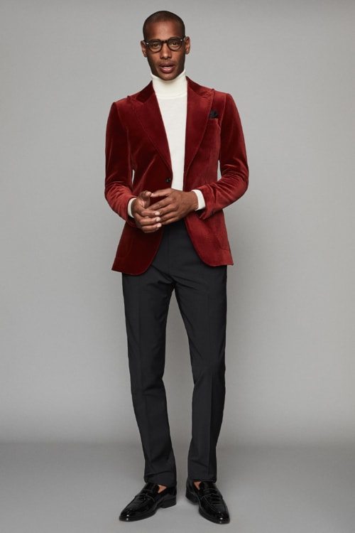 Men's cocktail attire outfit with red velvet blazer, black trousers and white roll neck