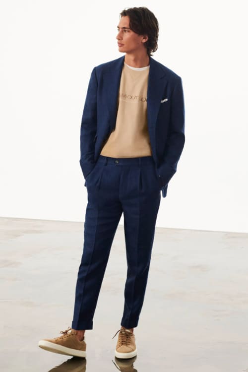 Men's navy suit with beige sweatshirt and sneakers outfit