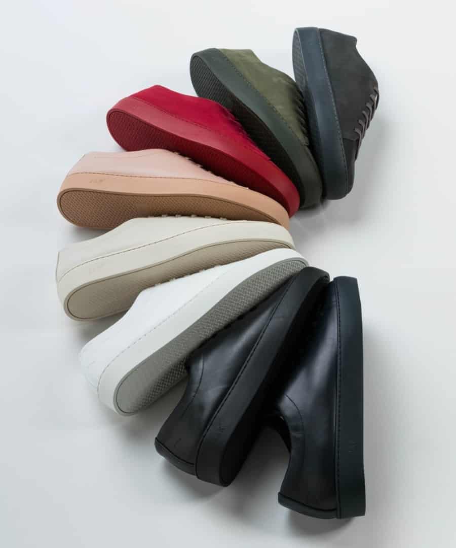 A selection of minimalist leather sneakers in a variety of colourways, including red, green, black, white, navy and beige