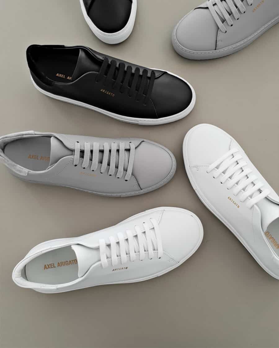 A top down view of a selection of minimalist sneakers in white, black and grey leather