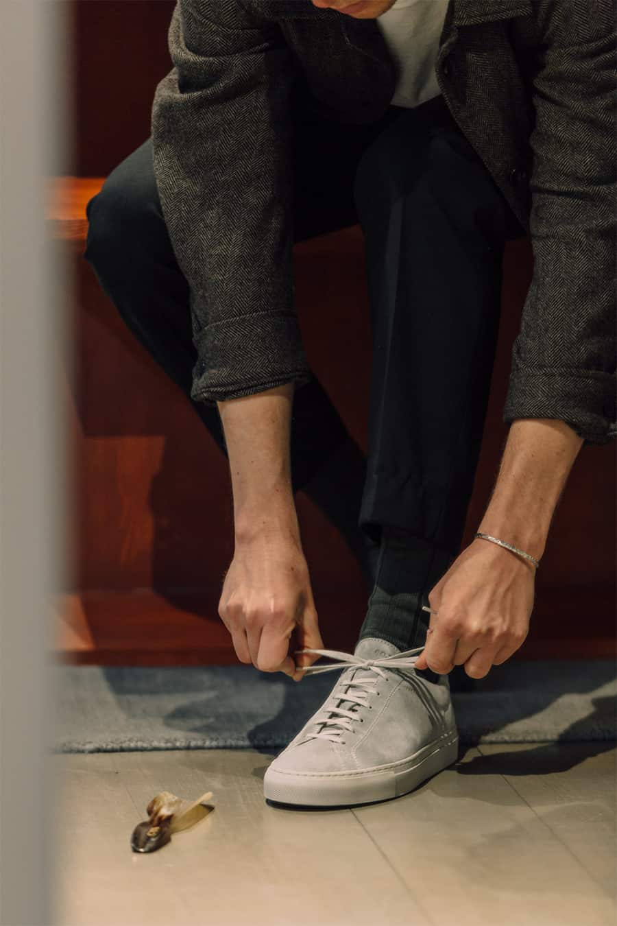 MAn tying laces on a pair of minimal grey suede sneakers
