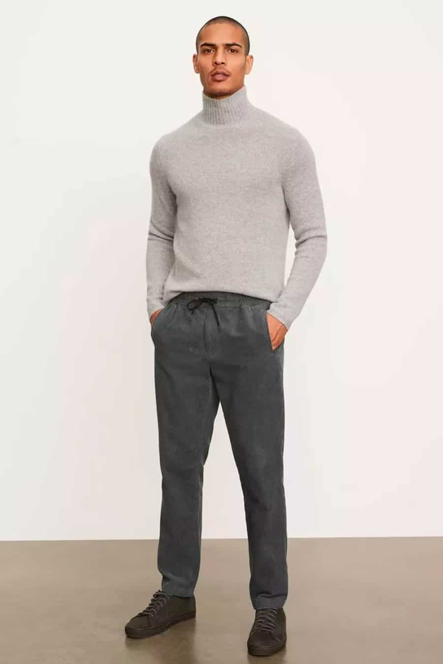 Men's grey pants, grey roll neck and suede sneakers outfit