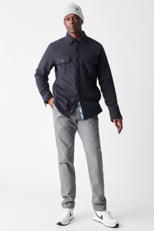 Men's grey jeans, blue flannel shirt, beanie and running shoes outfit