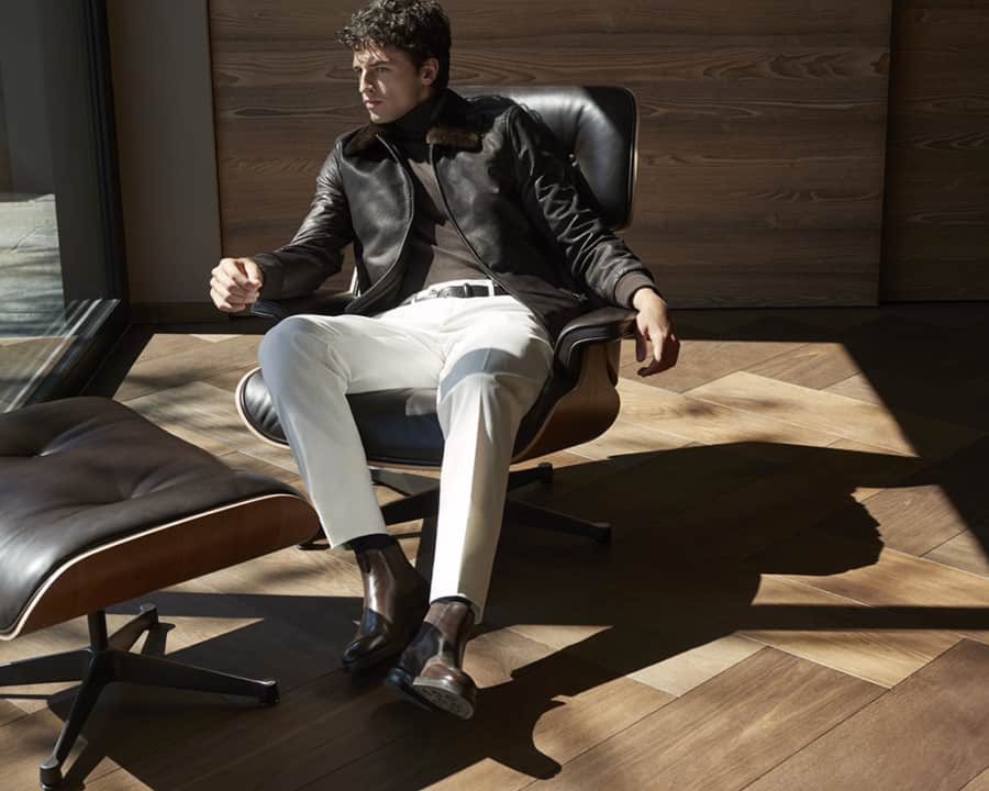Men's brown leather jacket worn with white trousers and brown leather Chelsea boots