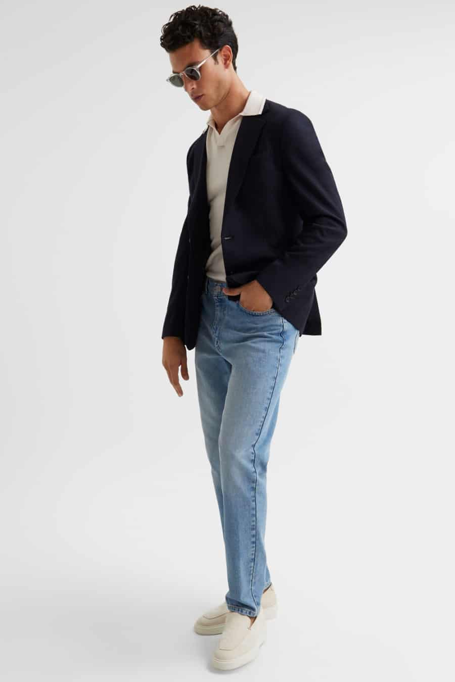 Men's light wash blue jeans, knitted polo shirt, navy unstructured blazer and suede loafers outfit