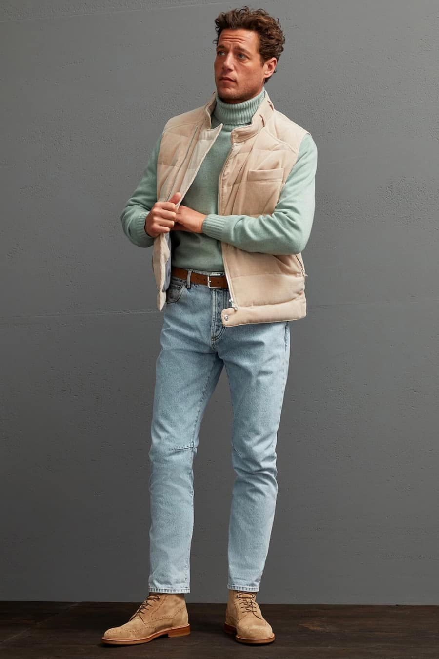 Men's light blue wash jeans, green turtleneck, gilet and suede boots outfit