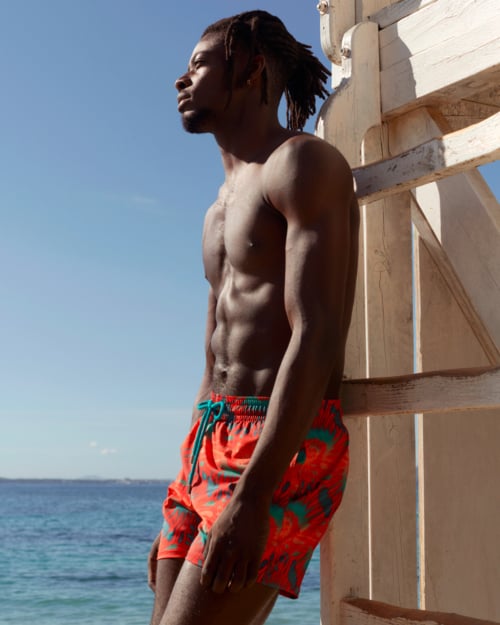 Black man wearing luxury red printed Vilebrequin swim shorts