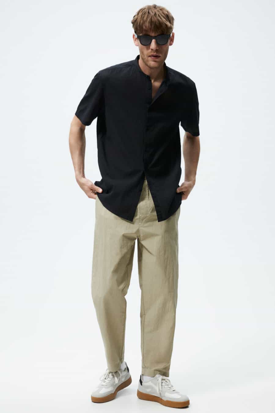 Men's wide legged khaki pants, black short sleeved shirt and white sneakers outfit